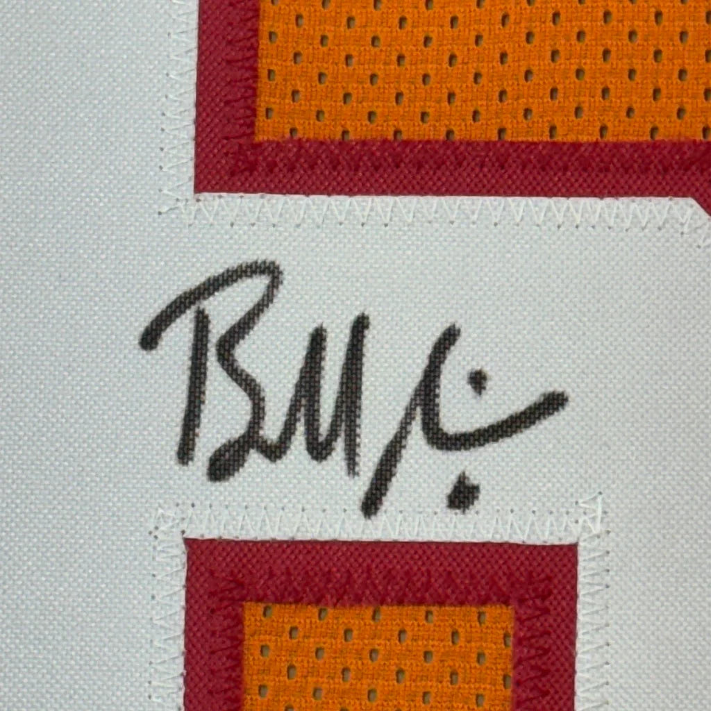 Black cursive signature on a white fabric patch bordered by red and orange mesh on framed Baker Mayfield throwback jersey