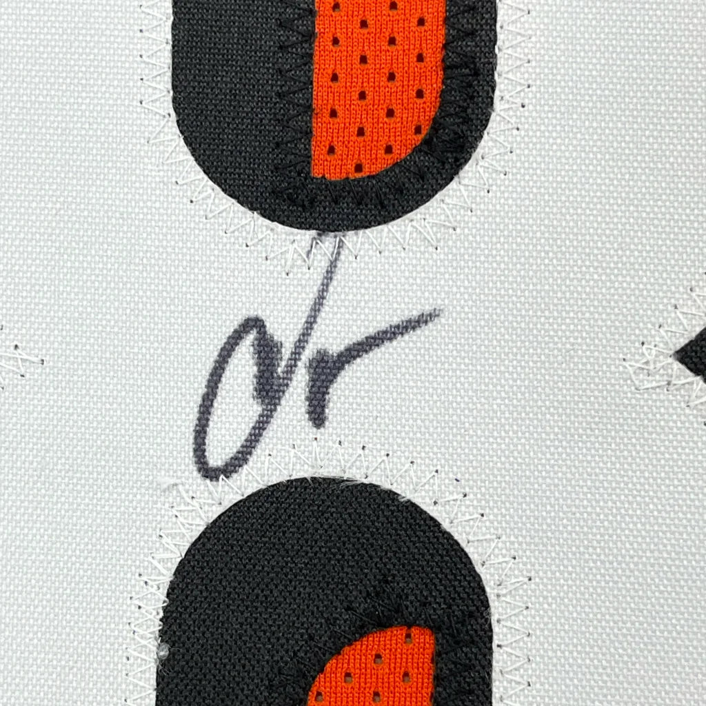 White fabric with black and orange semicircles and black signature in professionally framed Chad Ochocinco memorabilia