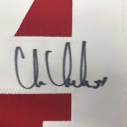 A black ink signature on a white and red framed autographed chris chelios detroit red hockey jersey