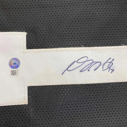 A white fabric tag with signature and authentication sticker attached to black perforated mesh on las vegas oakland football jersey