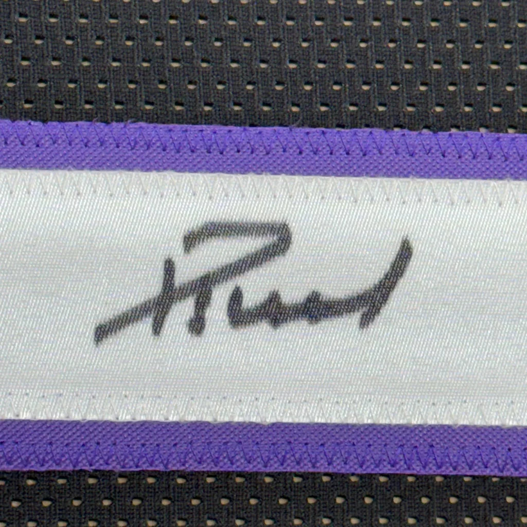 White fabric label with black Domantas Sabonis signature, purple stitching on black mesh