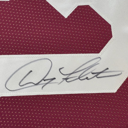 Maroon sports jersey with a white number and a black autograph.