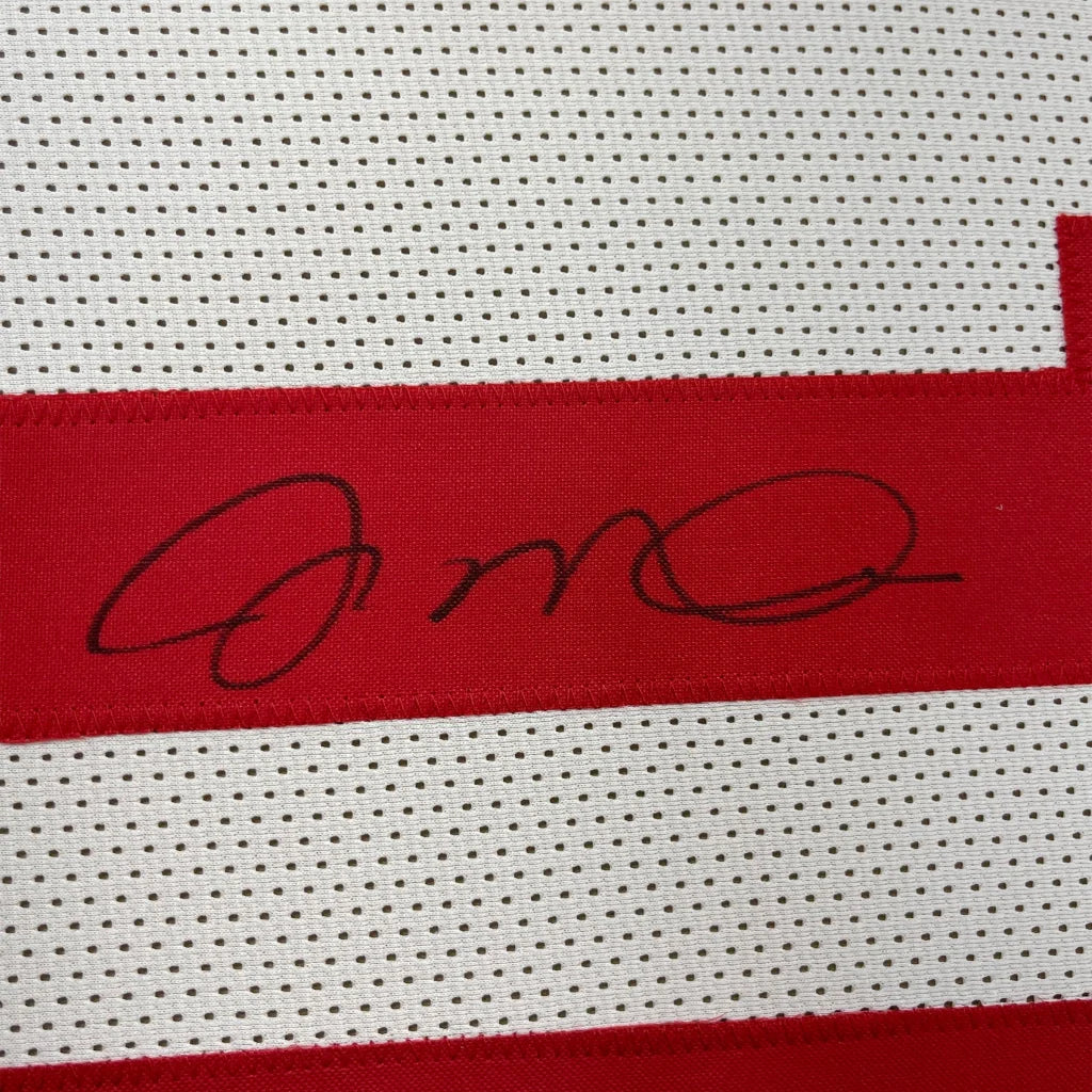 White athletic jersey with red stripe and black signature, perfect for display