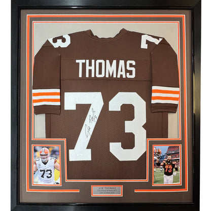 Framed autographed brown cleveland browns football jersey with white number 73 and name thomas displayed from back side