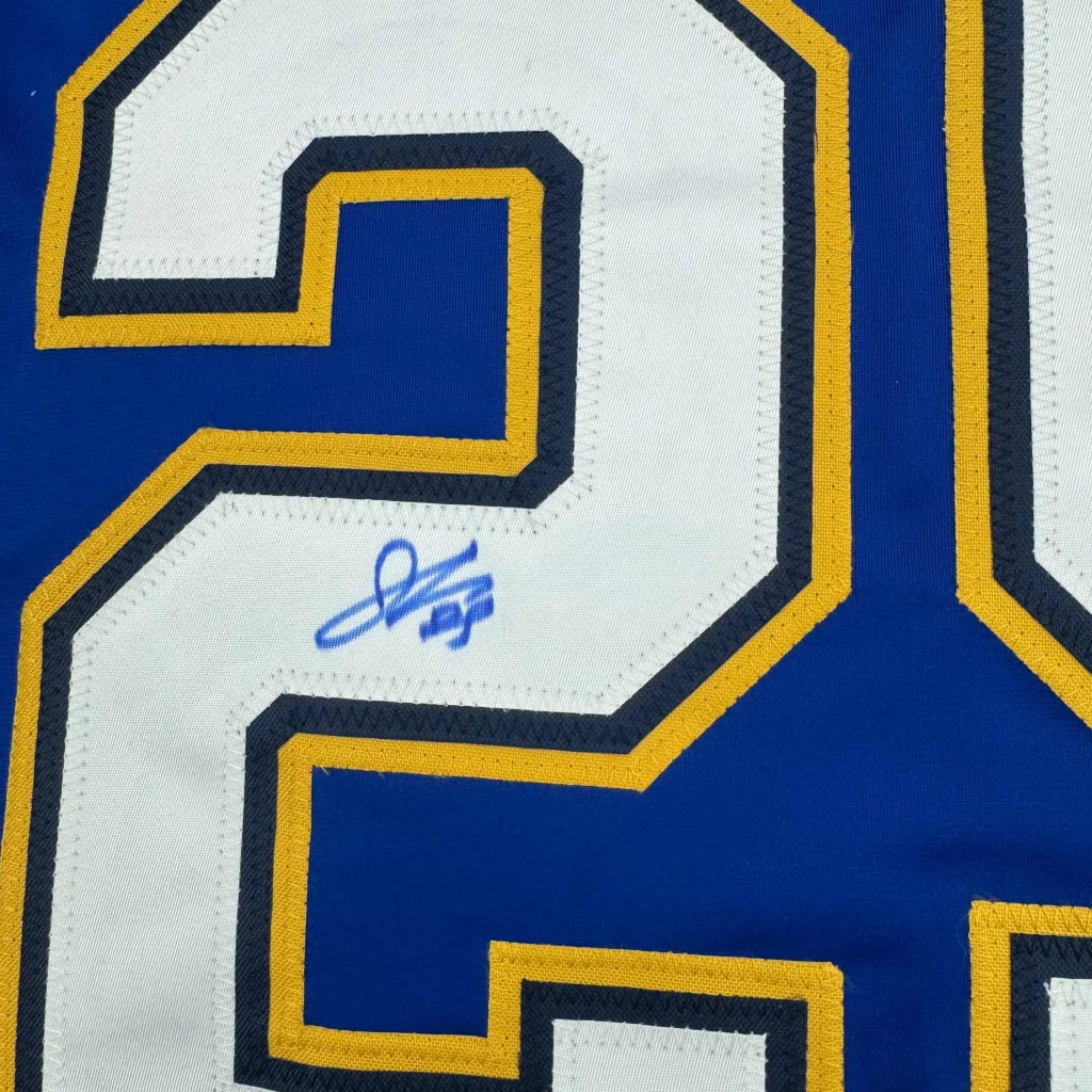 Blue and white hockey jersey with gold trim and a blue autograph, perfect for fans