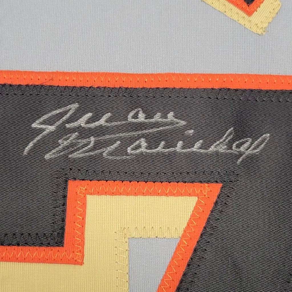 Black fabric patch with orange and beige geometric stitching and white embroidered signature on framed signed san francisco grey jersey