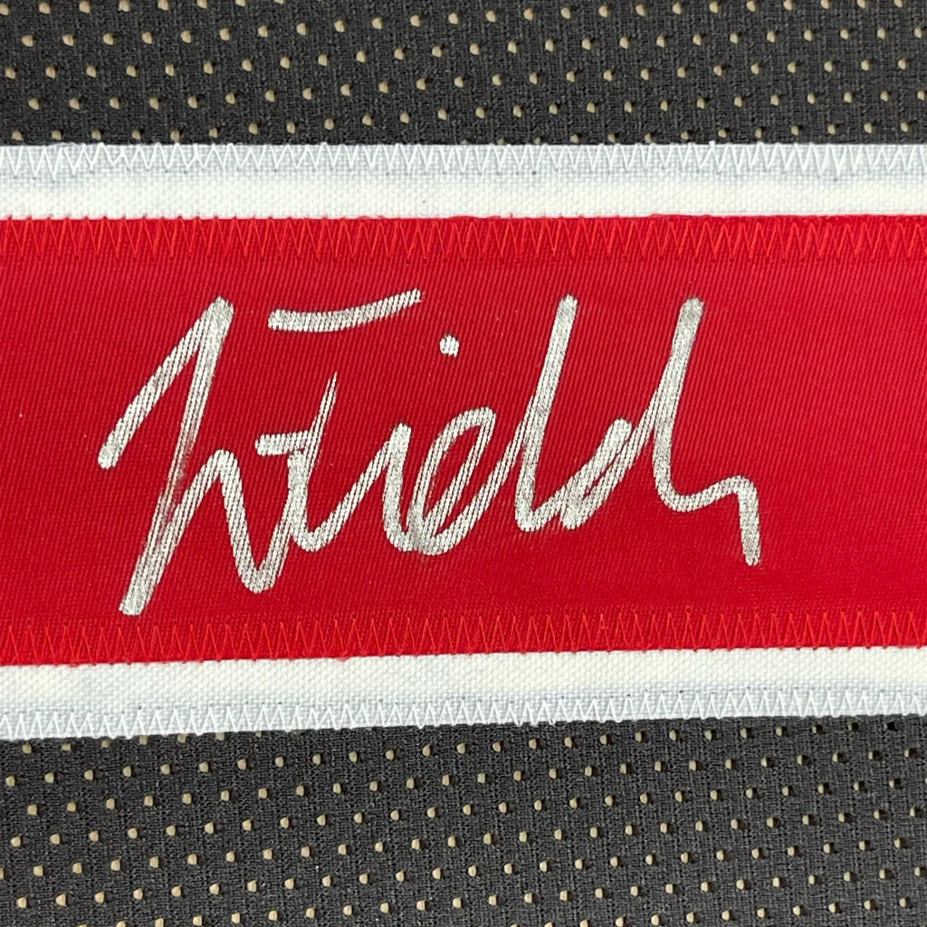 Red and white embroidered fields logo on black mesh fabric of framed autographed ohio state college football jersey