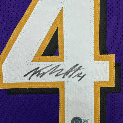 Framed autographed Baltimore purple and gold mesh football jersey with white number four and yellow outline by Kyle Hamilton