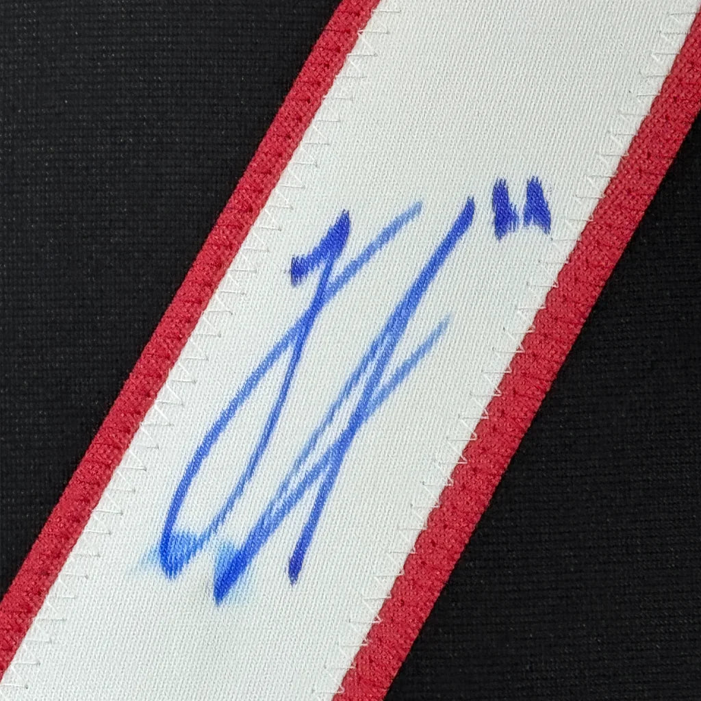 Framed autographed Logan Stankoven Carolina Hurricanes jersey with white red striped strap and blue signature, Beckett BAS COA