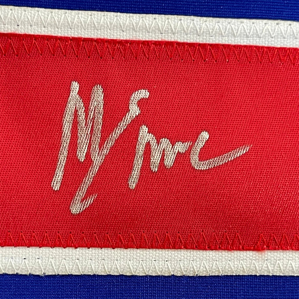 Red fabric label with white embroidered signature on framed autographed mike eruziño 1980 united states hockey jersey