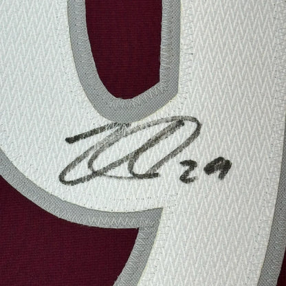 A close-up of a white and maroon colorado hockey jersey with gray trim and an embroidered black signature