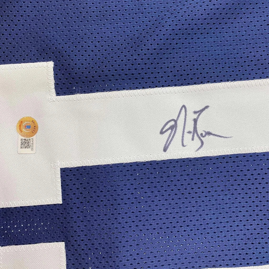 Autographed blue football jersey with white stripes in a frame with action photos