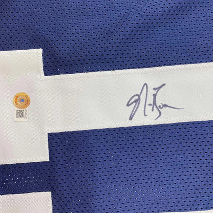 Autographed blue football jersey with white stripes in a frame with action photos