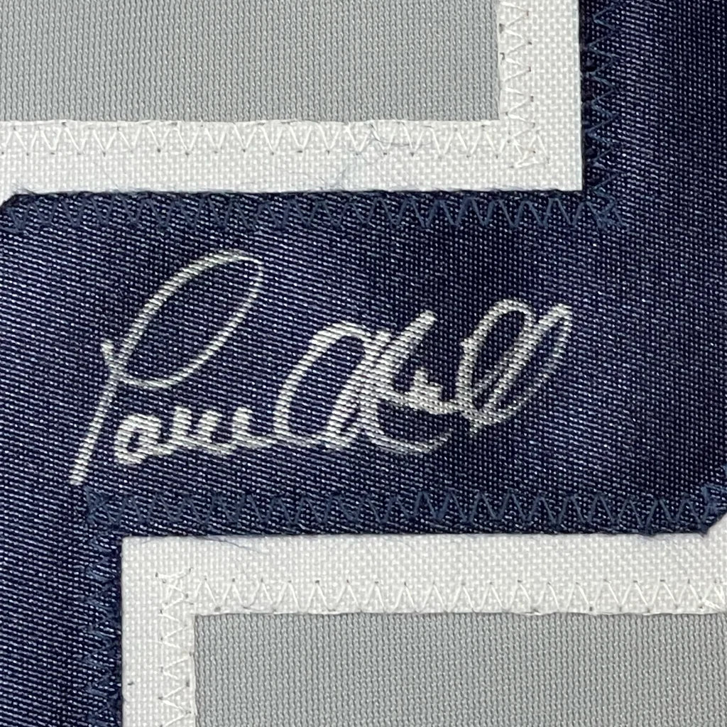 Dark blue fabric patch with white embroidery on professionally framed Paul ONeill York Grey Baseball Jersey