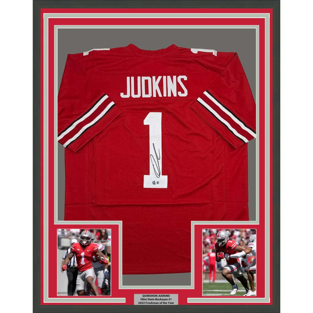 Framed autographed ohio state red football jersey with white lettering signed by quinshon judkins back side visible
