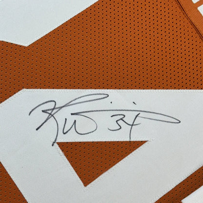 Orange and white signed football jersey with player photos in a frame