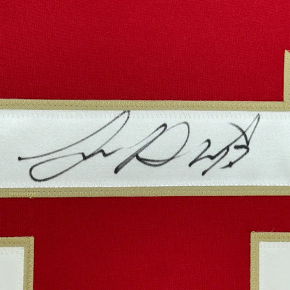 Red fabric item with white gold border and Sam Reinhart signature, professionally framed for your man cave