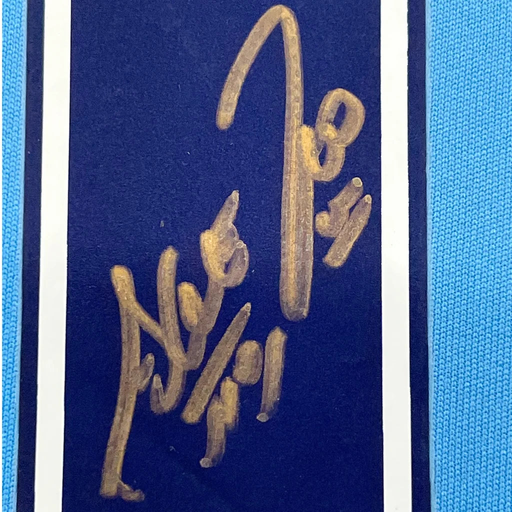 Blue card with gold signature next to Sergio Agüero Manchester City jersey frame