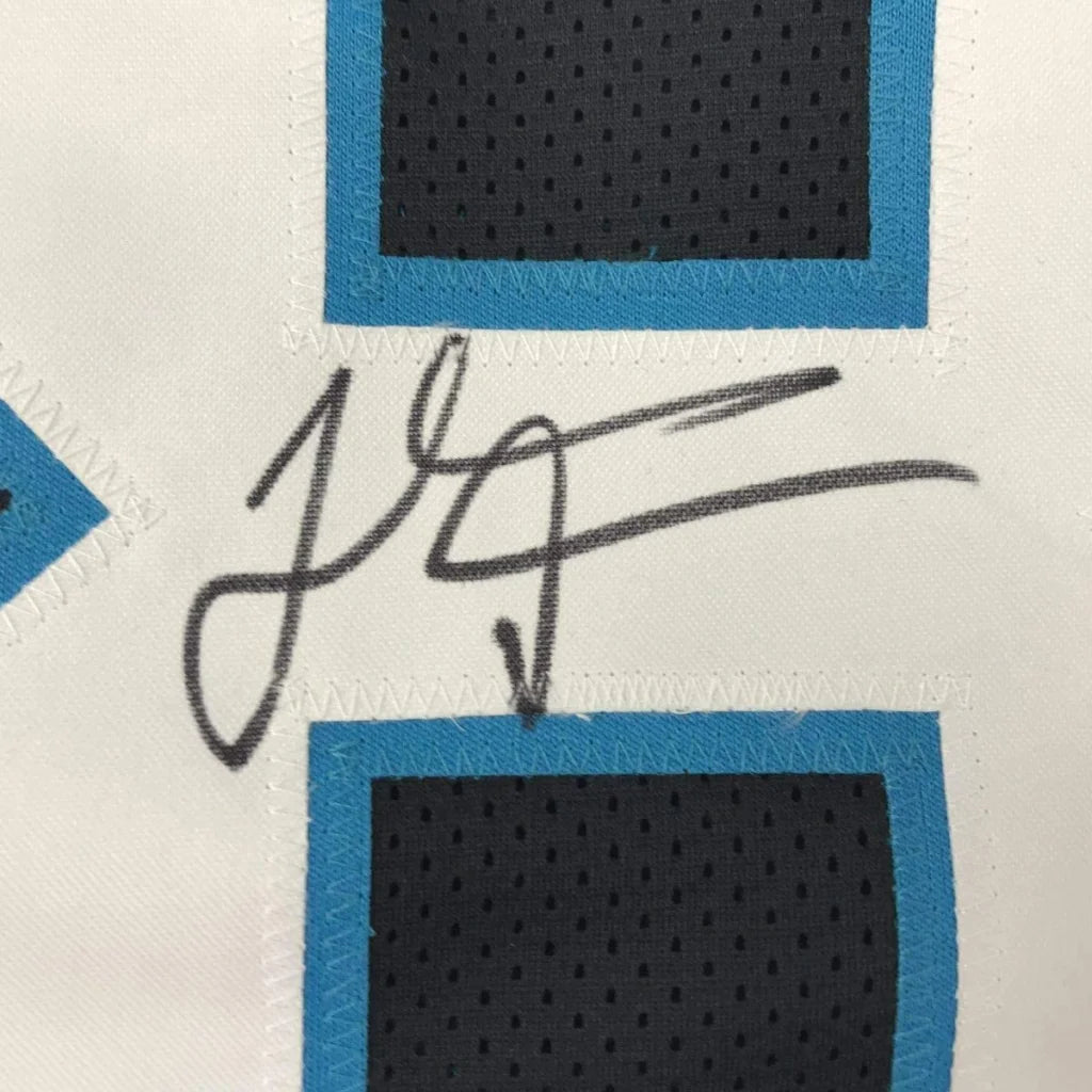 Black ink signature on a white Carolina black football jersey with blue and black mesh panels framed 35x39 inches