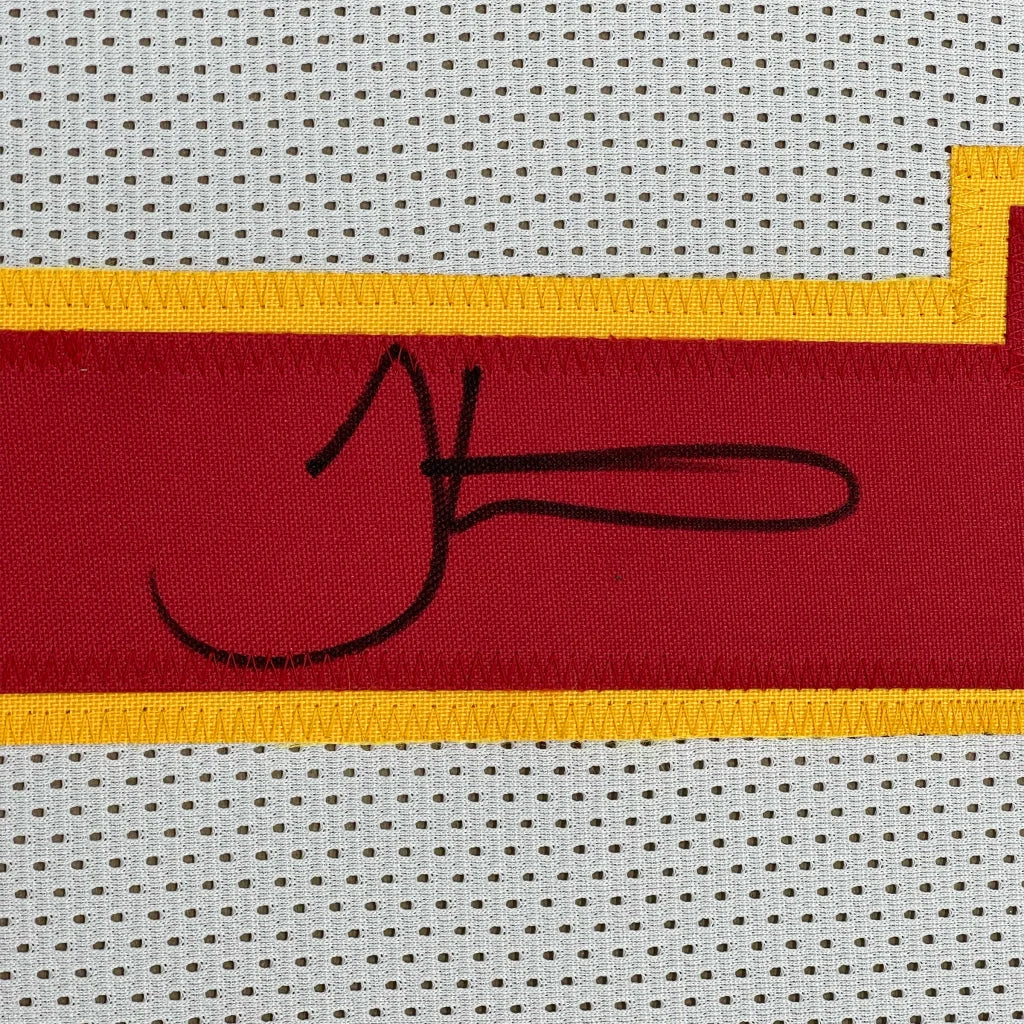 A black embroidered signature on a red and yellow Kansas City white football jersey in a framed display