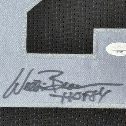 Black and white signed football jersey with autograph, photos, and commemorative plaque