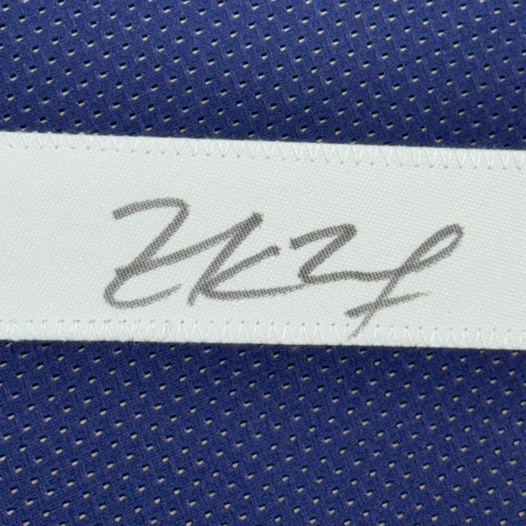 White label with gray cursive signature stitched on blue mesh jersey