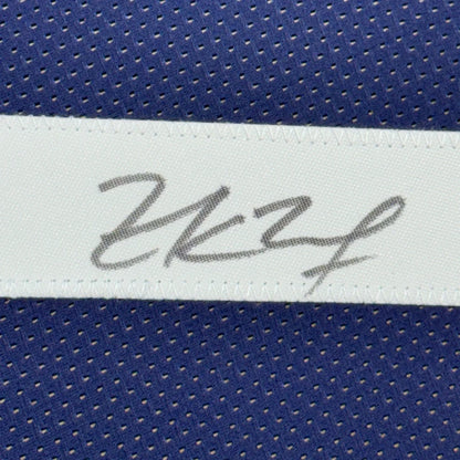 White label with gray cursive signature stitched on blue mesh jersey