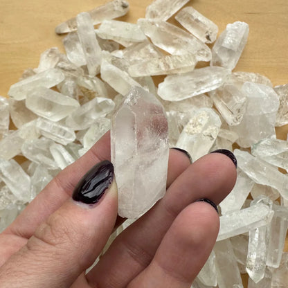 Hand holding translucent Brazilian quartz crystal with black nails