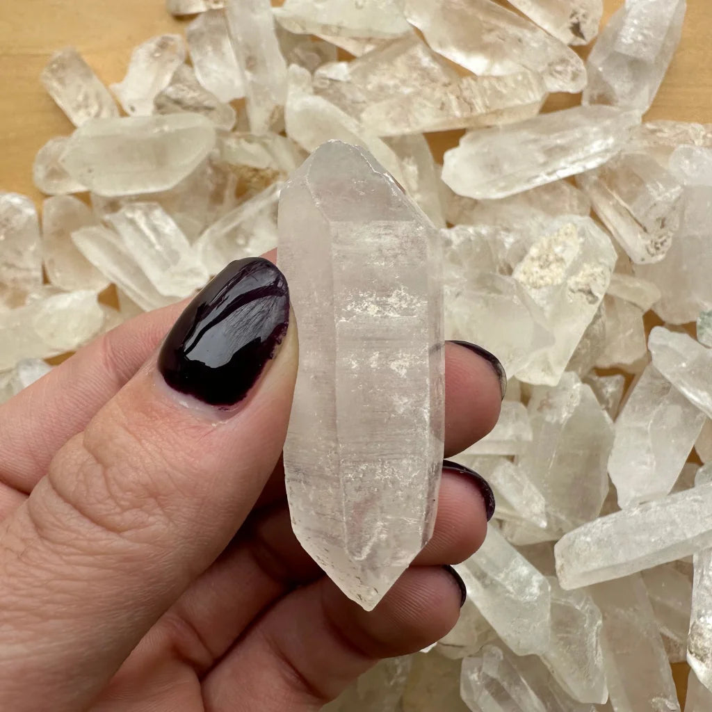 Genuine Brazilian quartz crystal point held by fingers with dark nails