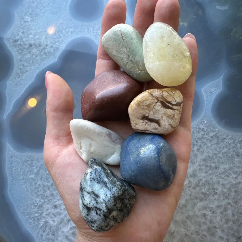 Hand holding giant large tumbled stone collection in earthy tones