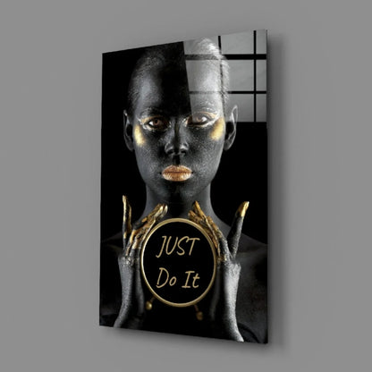 Golden woman with metallic skin holding Just Do It emblem on glass wall art