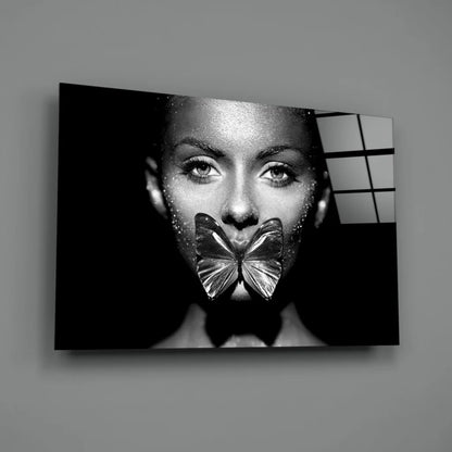 Black-and-white woman with glittery skin and metallic butterfly over mouth in Glitter Butterfly Kiss glass wall art