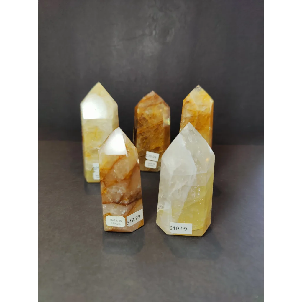 Four polished translucent yellow and orange golden healer quartz obelisk tower sculptures with natural inclusions