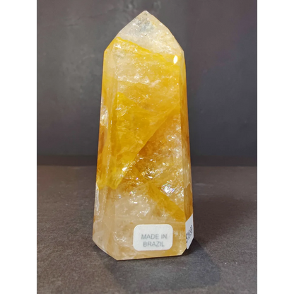 A translucent yellow citrine golden healer quartz polished obelisk tower sculpture with faceted sides and inclusions
