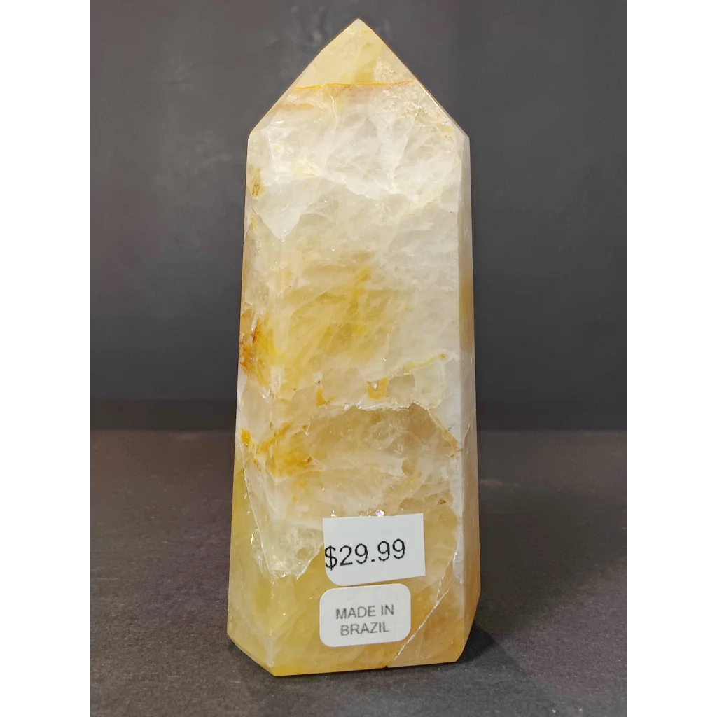 A translucent yellow-orange polished golden healer calcite obelisk tower sculpture with layered banding and pointed top