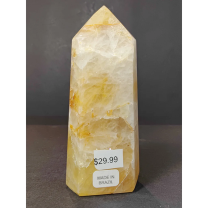 A translucent yellow-orange polished golden healer calcite obelisk tower sculpture with layered banding and pointed top