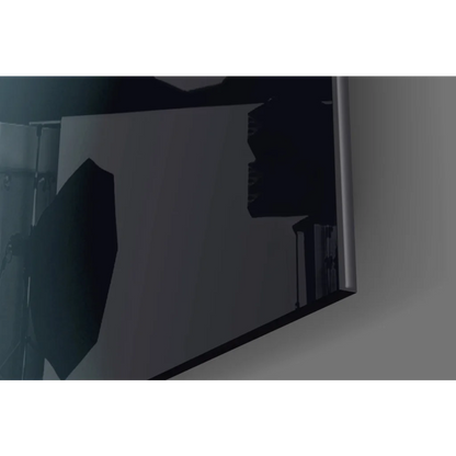 Sleek silver-framed glass wall art with reflective screen showing dark studio lighting silhouettes