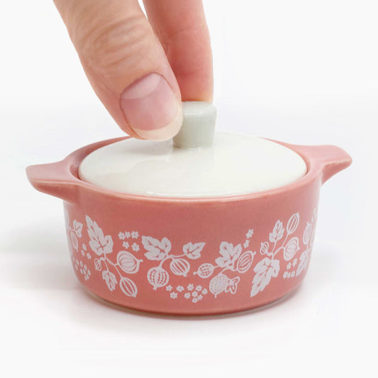 Hand lifting the white lid of the pink Gooseberry mini casserole trinket box