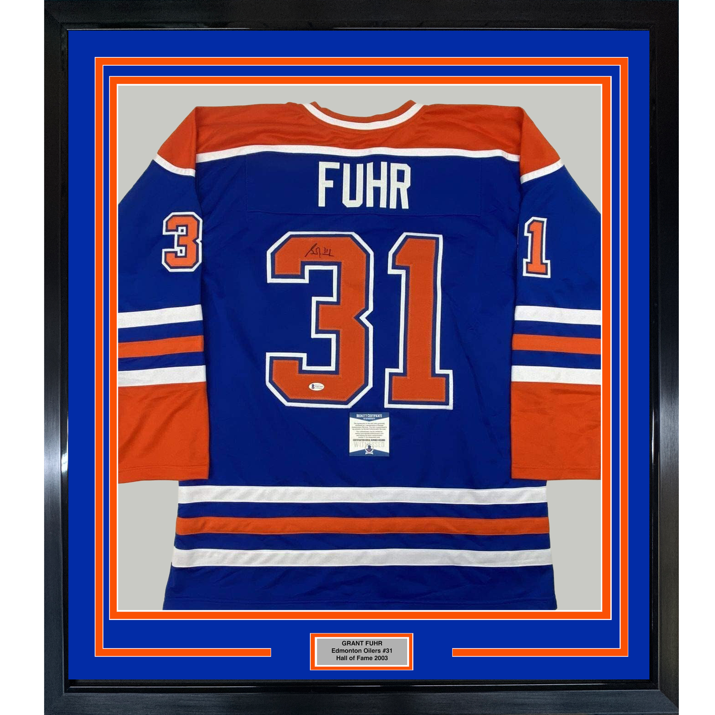 Framed Edmonton Oilers blue hockey jersey number 31 with "FUHR" nameplate and authenticity certificate displayed behind glass with orange and blue matting.
