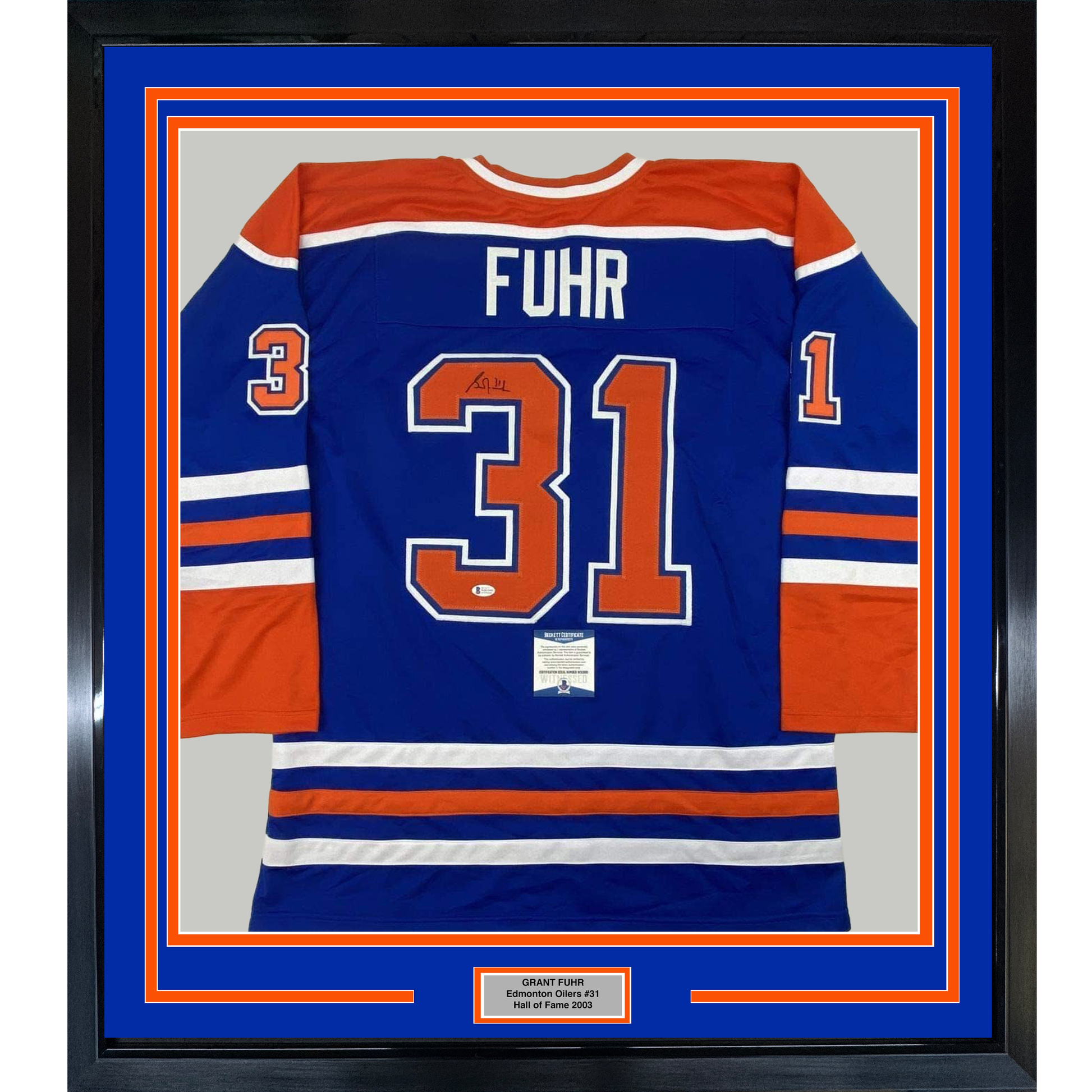 Framed Edmonton Oilers blue hockey jersey number 31 with "FUHR" nameplate and authenticity certificate displayed behind glass with orange and blue matting.