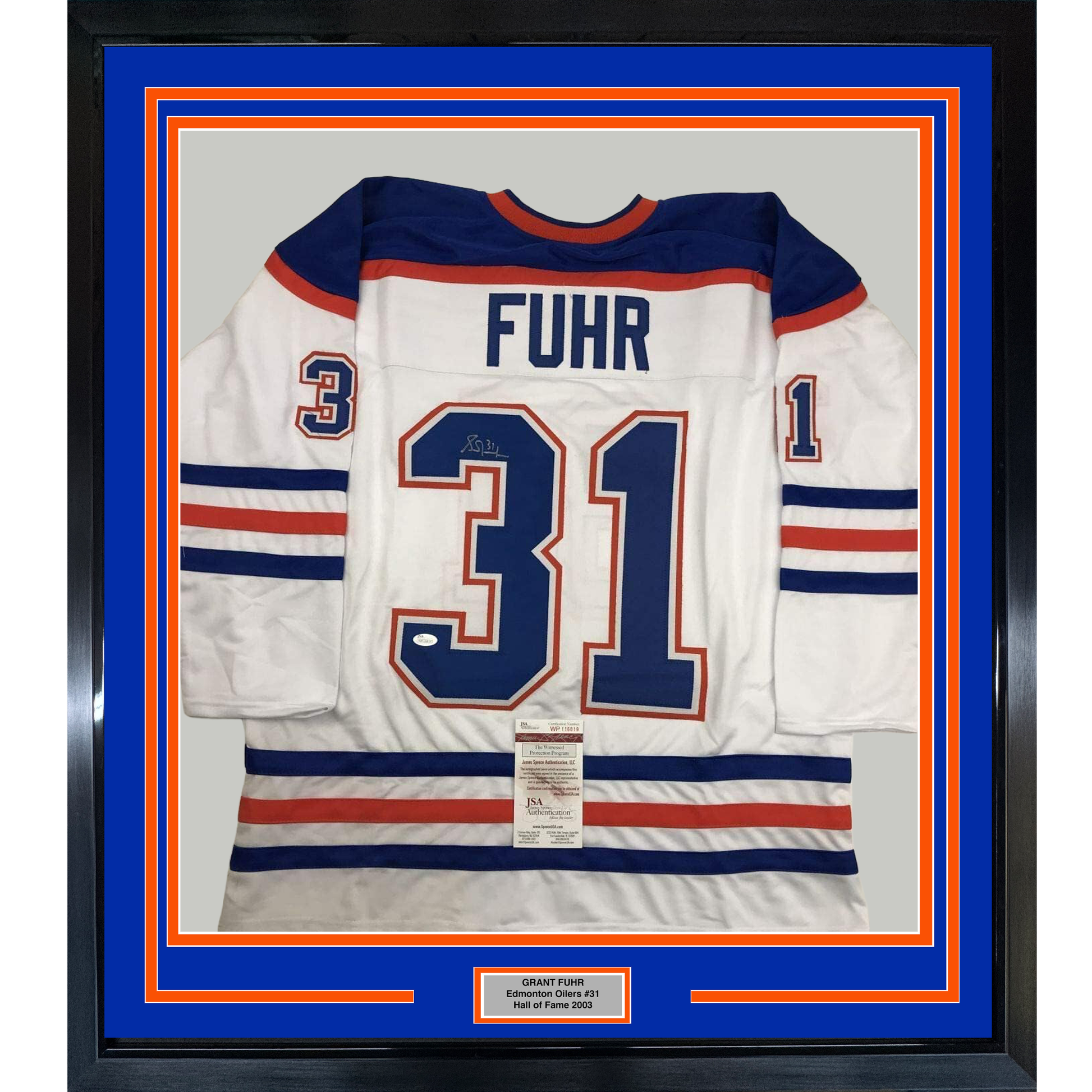 Framed white Edmonton Oilers hockey jersey number 31 with "FUHR" nameplate and JSA authentication certificate, displayed against blue and orange matting with black frame.