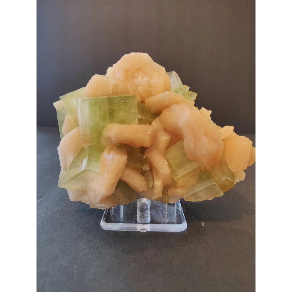Green apophyllite cubes with peach stilbite specimen on acrylic stand