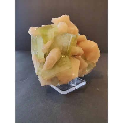 Green apophyllite cubes with peach stilbite specimen on acrylic stand