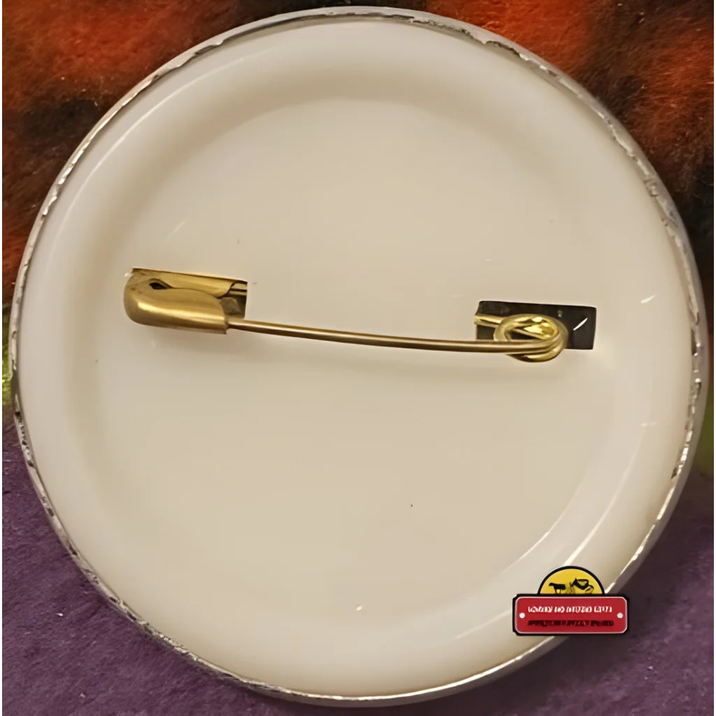 Gold safety pin on a white surface with Groove Surfer California Raisin Tin Pin design