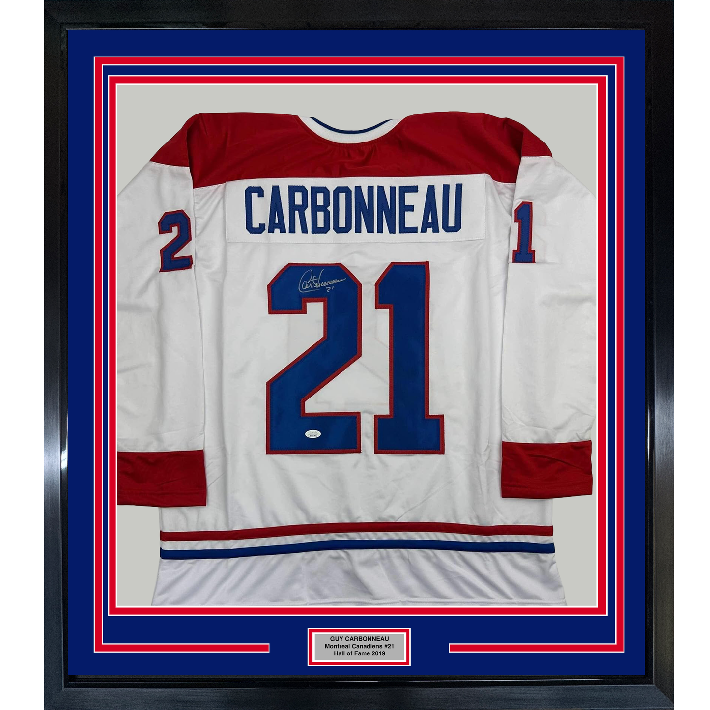 Framed Montreal Canadiens white hockey jersey #21 with Carbonneau nameplate, signed, displayed front-facing with red and blue borders.