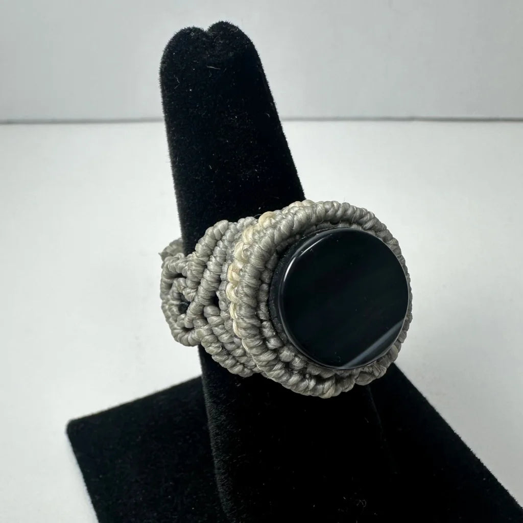 Chunky handmade woven ring with textured gray macrame band and smooth black stone center