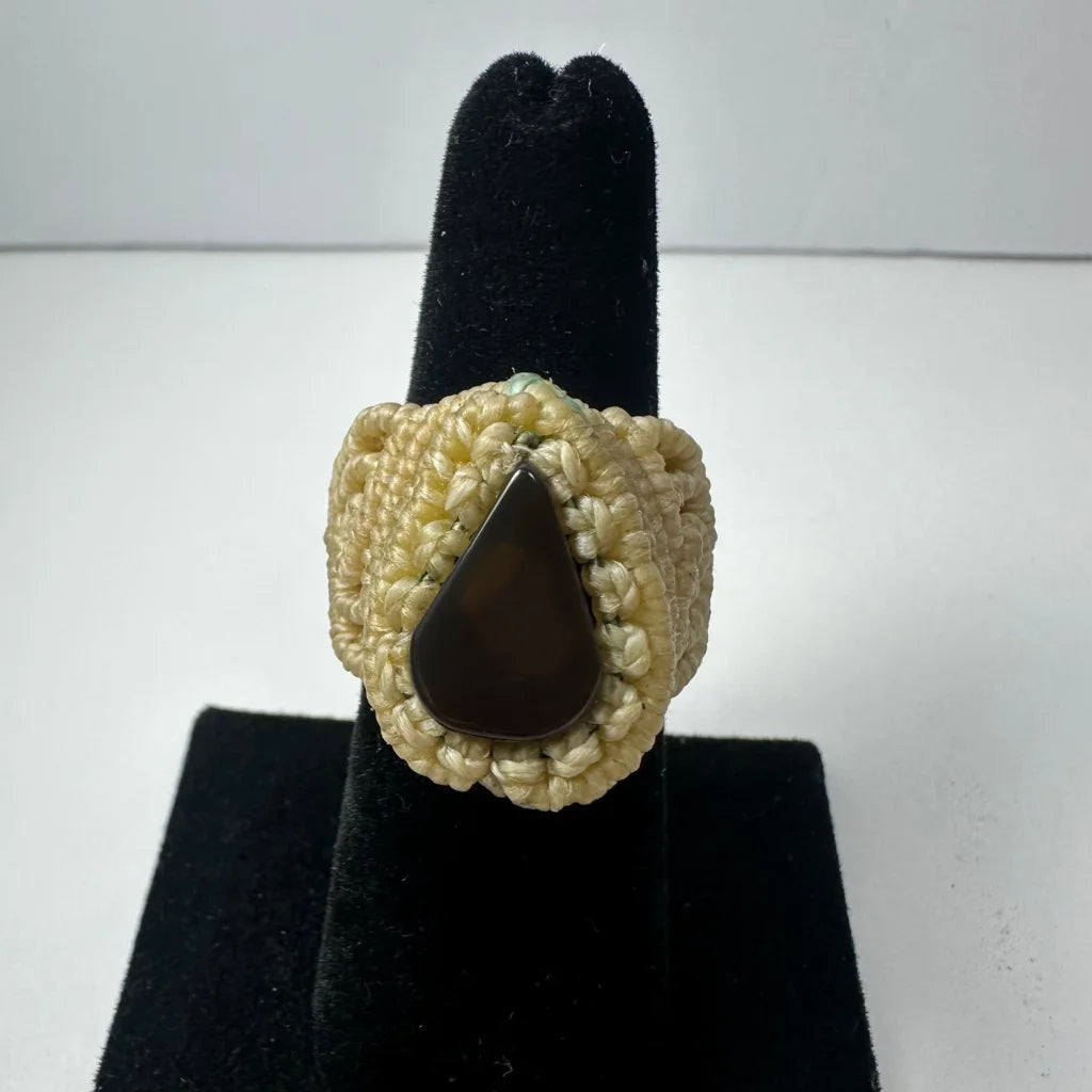Cream-colored handmade woven ring with dark brown teardrop stone