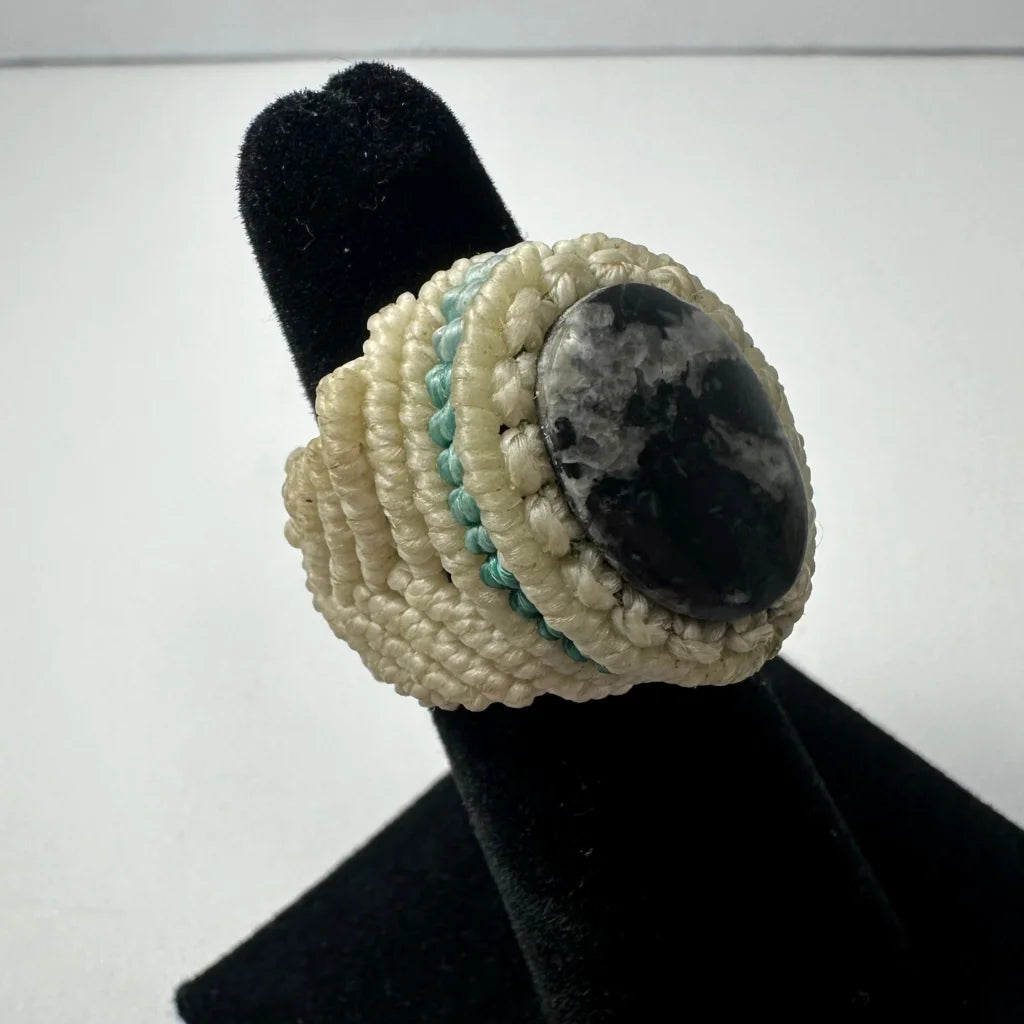Cream-colored handmade woven ring with oval black and white stone center