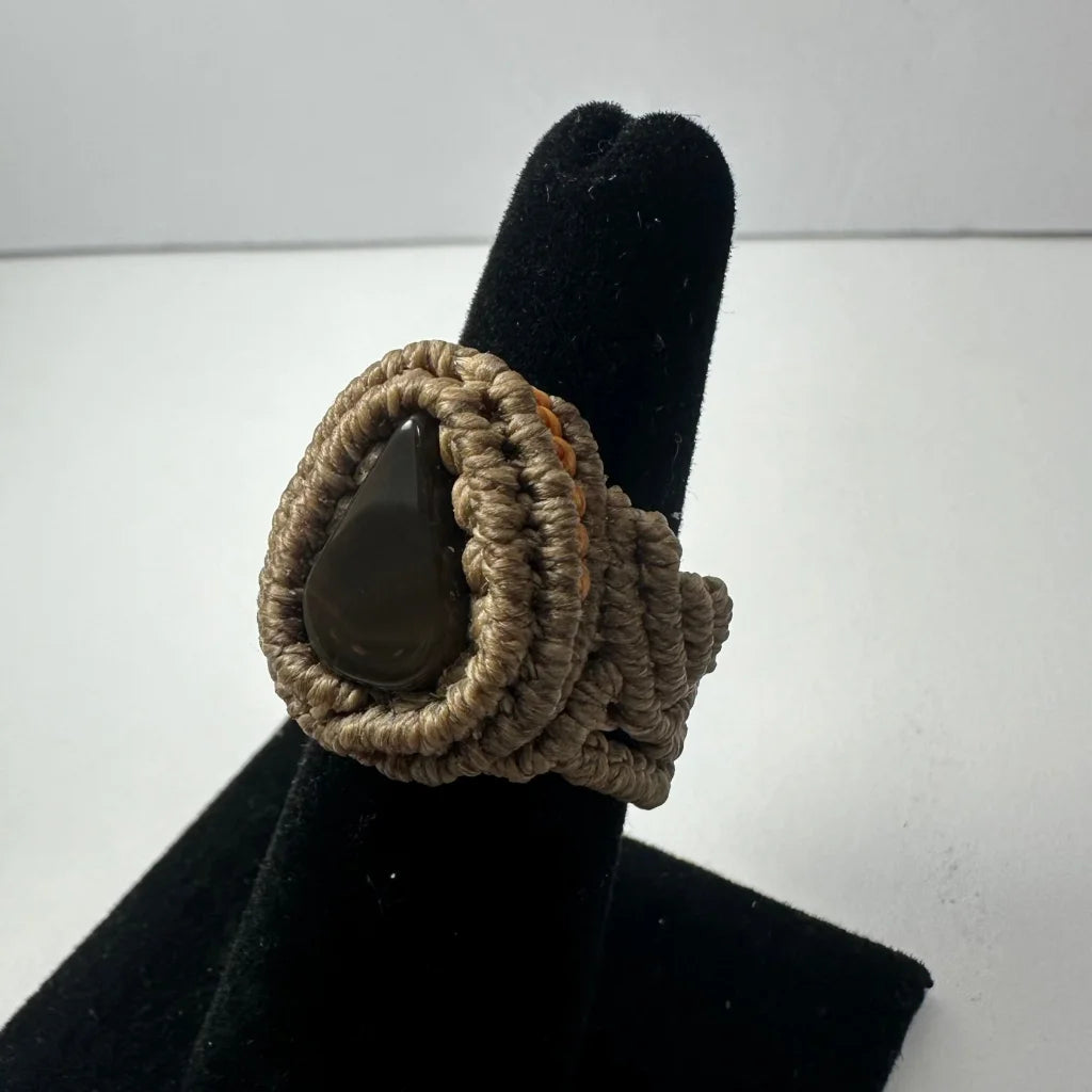 Handmade woven ring with dark teardrop stone in beige knotwork band