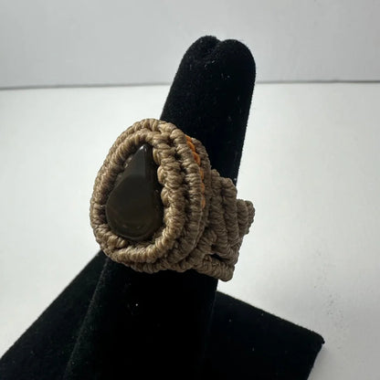 Handmade woven ring with dark teardrop stone in beige knotwork band